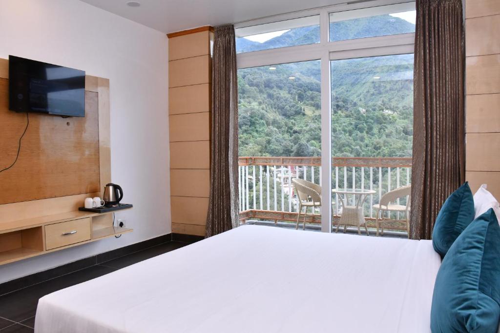 a bedroom with a bed and a large window at Hotel The Crown in Dharamshala