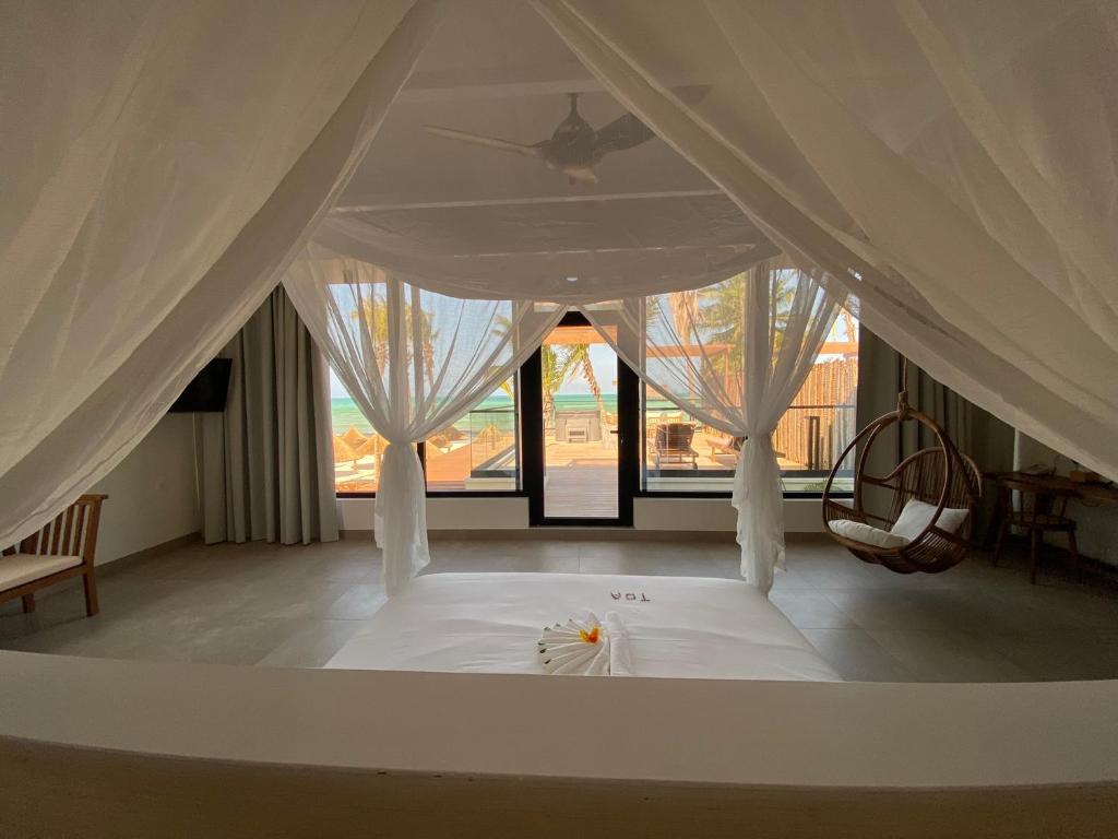 a bedroom with a white bed with white curtains at TOA Hotel & Spa Zanzibar in Pongwe