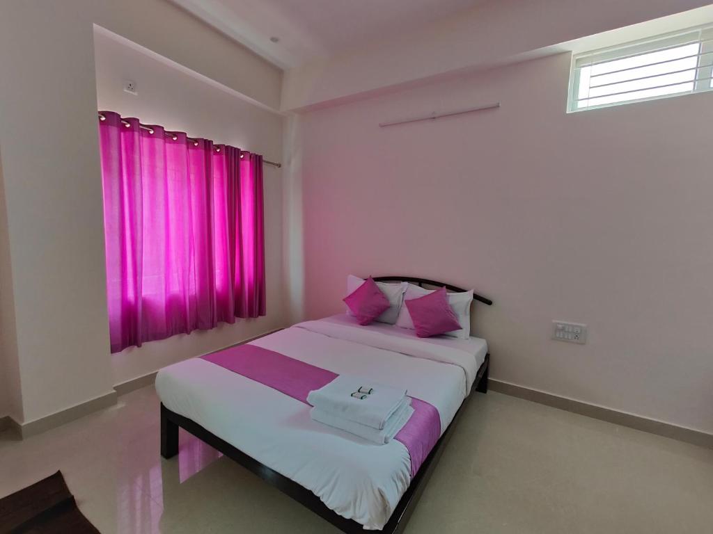 1 dormitorio con 1 cama grande y cortinas rosas en Lishan Apartment, en Mysore