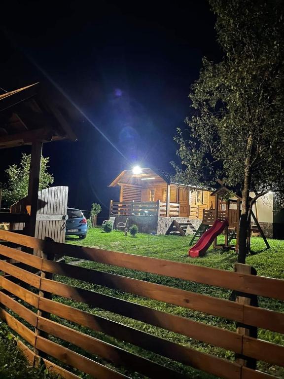 a fence in a yard with a playground at night at Wooden House Ripac in Bihać