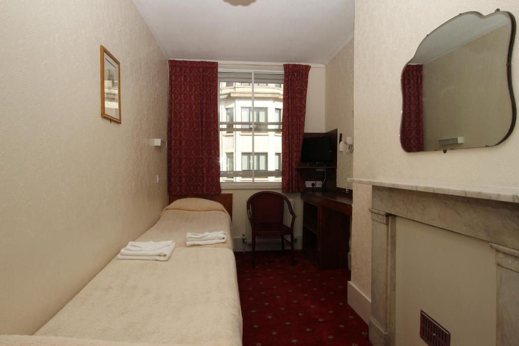a hotel room with two beds and a mirror at Ridgemount Hotel in London