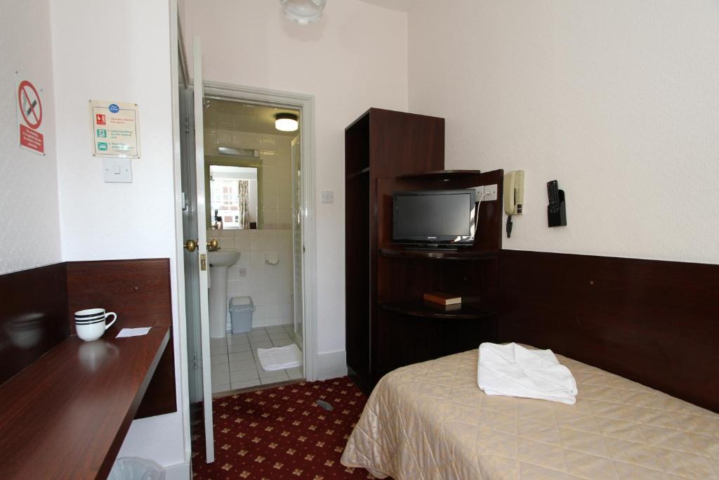 a room with a bed and a television and a bathroom at Ridgemount Hotel in London