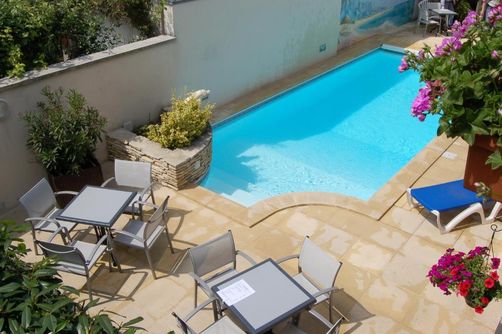 an overhead view of a swimming pool with tables and chairs at Logis Hotel au tambour in Reims