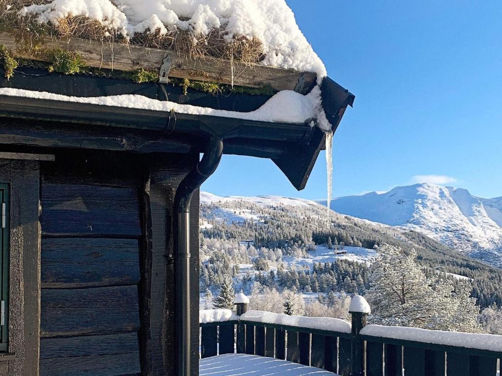 een met sneeuw bedekt dak van een hut met uitzicht op een berg bij Holiday home Byrkjelo in Byrkjelobrua