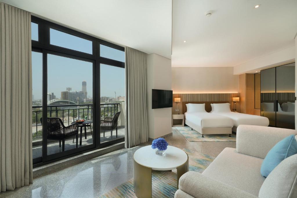 ドバイにあるArabian Park Dubai, an Edge by Rotana Hotelのベッドとリビングルームがあるホテルの部屋