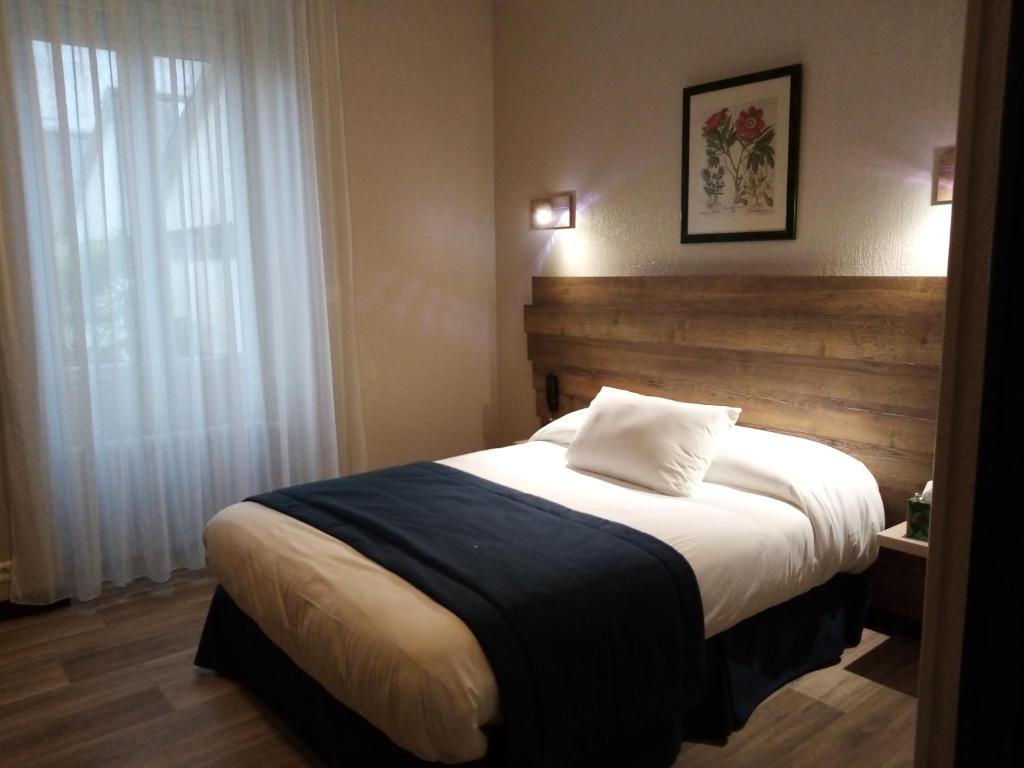 a bedroom with a large bed with a wooden headboard at Du coq à l'âne in LʼAbsie