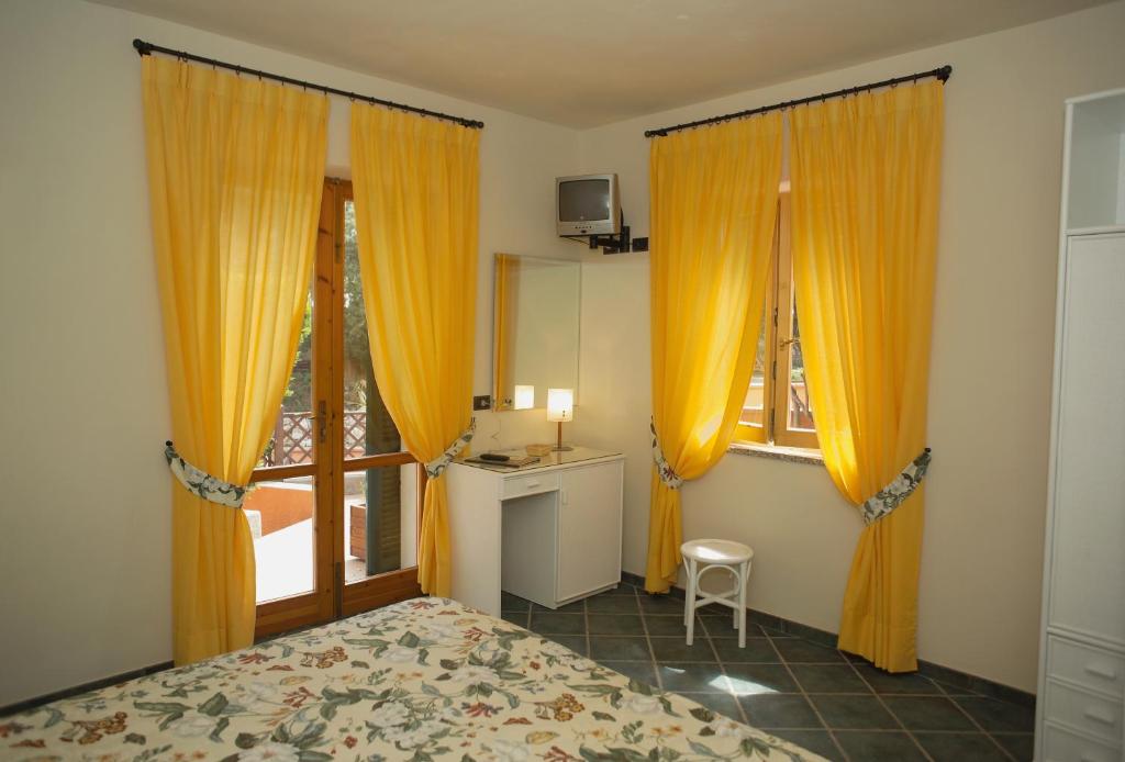 a bedroom with orange curtains and a bed and a window at Hotel Danila in Portoferraio