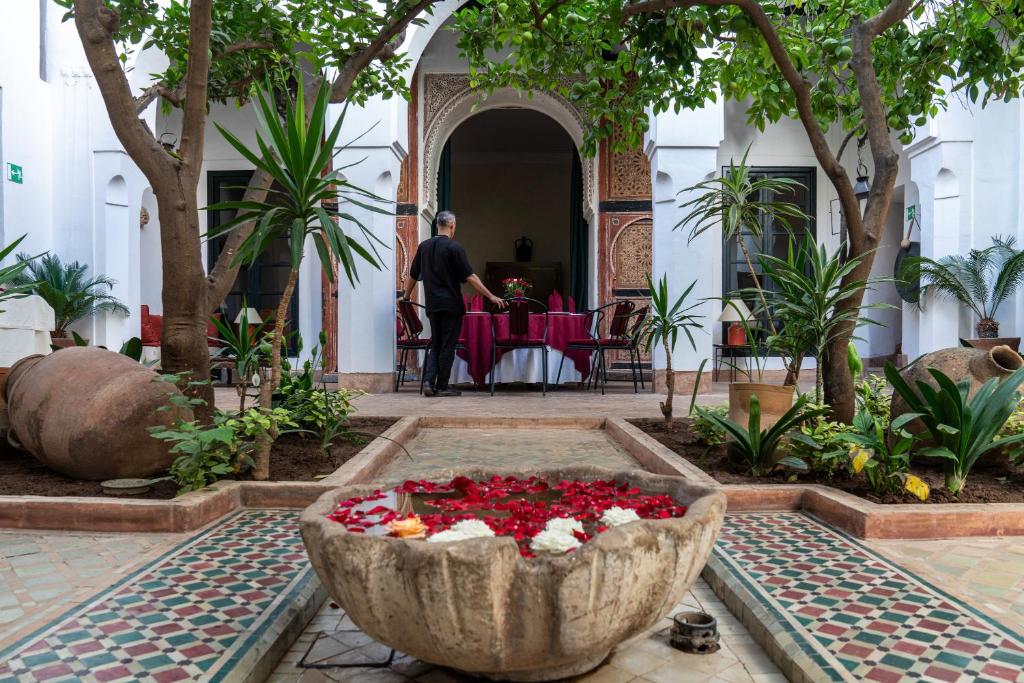 a man standing in a courtyard with a bowl of flowers at Riyad El Cadi in Marrakech