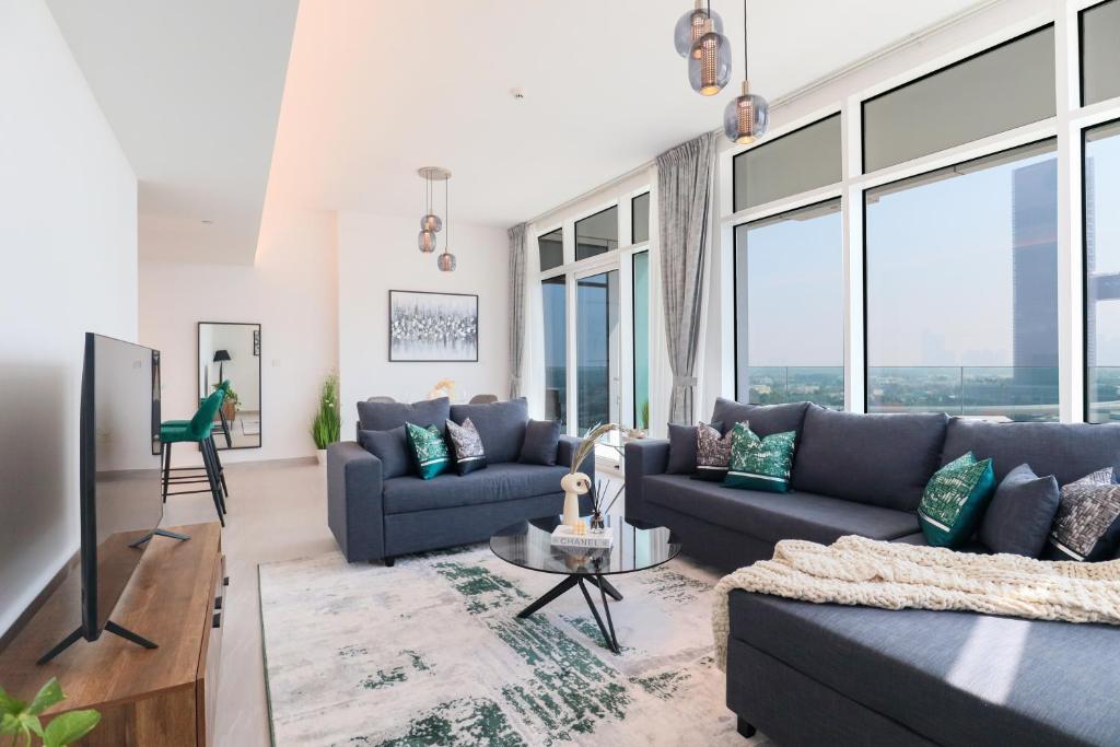 - un salon avec des canapés bleus et de grandes fenêtres dans l'établissement HiGuests - Spacious Apt Near Zabeel Park With Panoramic Views, à Dubaï