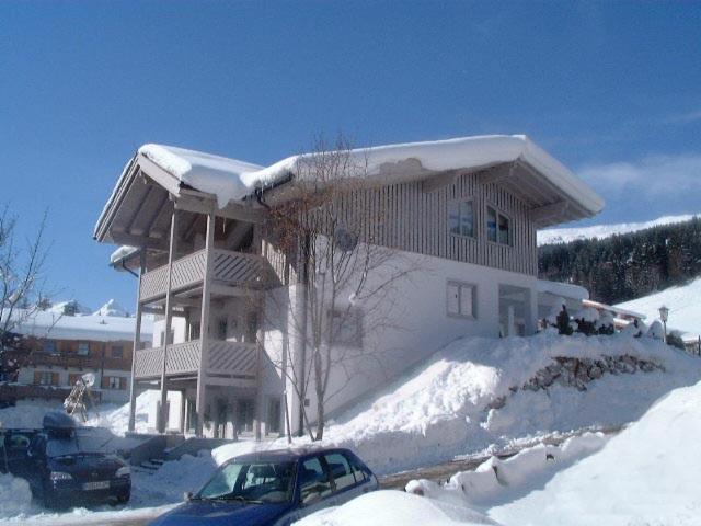 a house covered in snow with a car parked in front at Chalet Birkenhof in Saalbach Hinterglemm