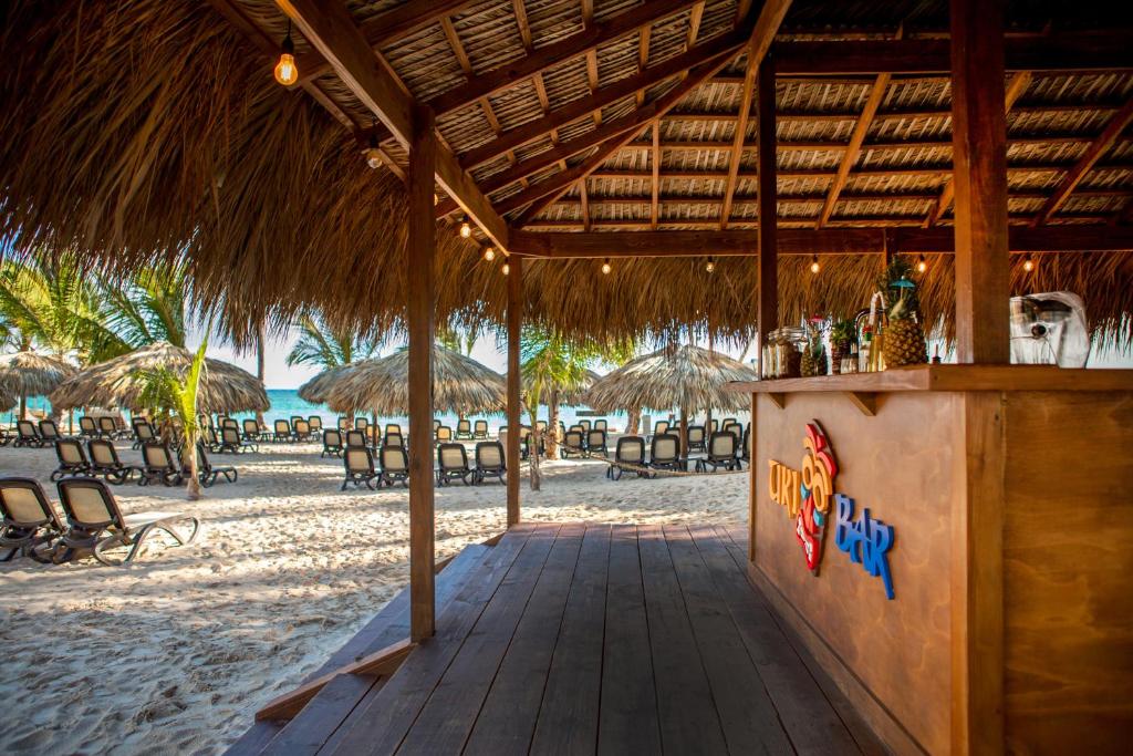 a bar on the beach with chairs and umbrellas at Impressive Premium Punta Cana - All Inclusive in Punta Cana