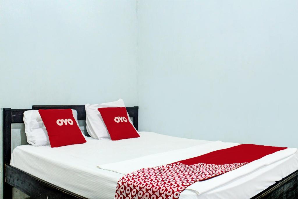 a bed with red and white pillows on it at OYO 91720 Hotel Yotowawa in Kupang