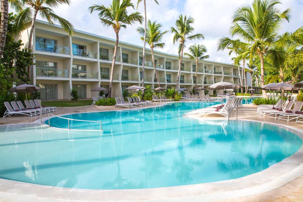 una piscina en el complejo con sillas y palmeras en Impressive Premium Punta Cana - All Inclusive, en Punta Cana