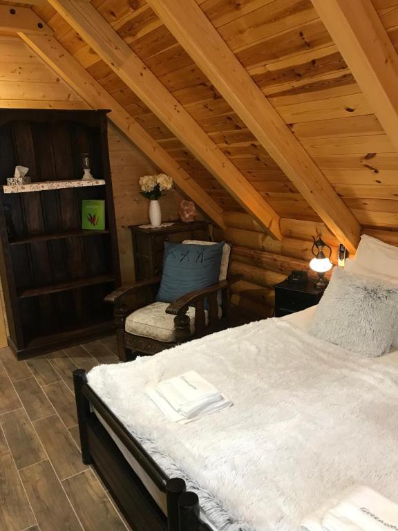 a bedroom with a bed and a chair in a attic at Greenwood Rönkház in Gárdony