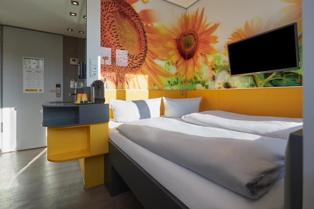 a bedroom with two beds and a tv on the wall at Buddy Hotel in Munich