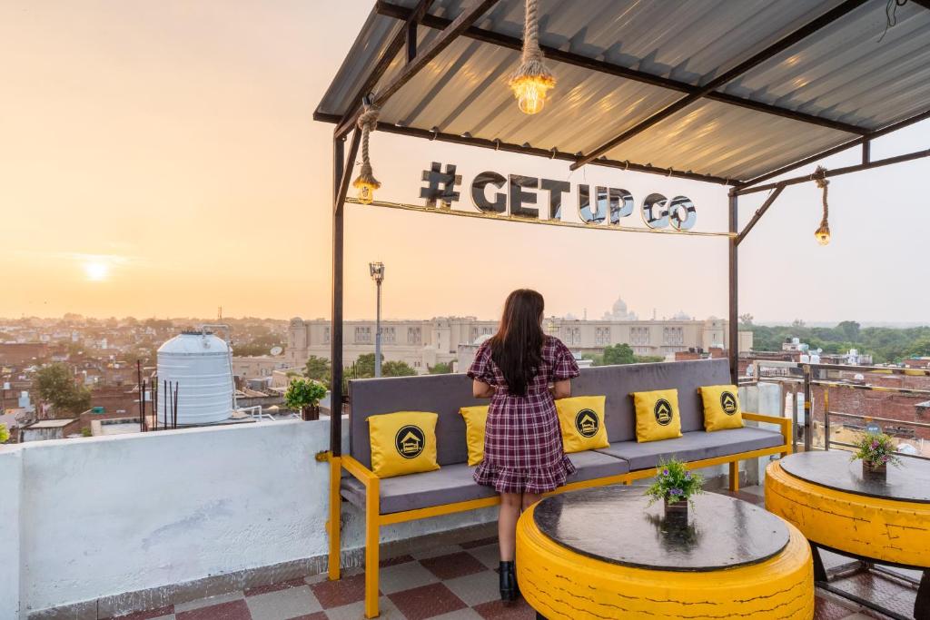 a woman sitting on a bench on a roof at The Hosteller Agra in Agra