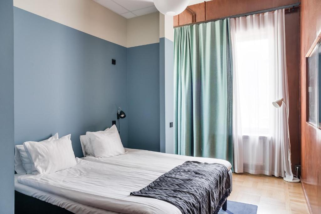 a bedroom with a bed with blue walls and a window at The Nooq Malmö - Hotel & Studios in Malmö