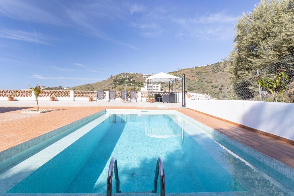 una piscina de agua azul y una casa en Villa Benama, en Torrox
