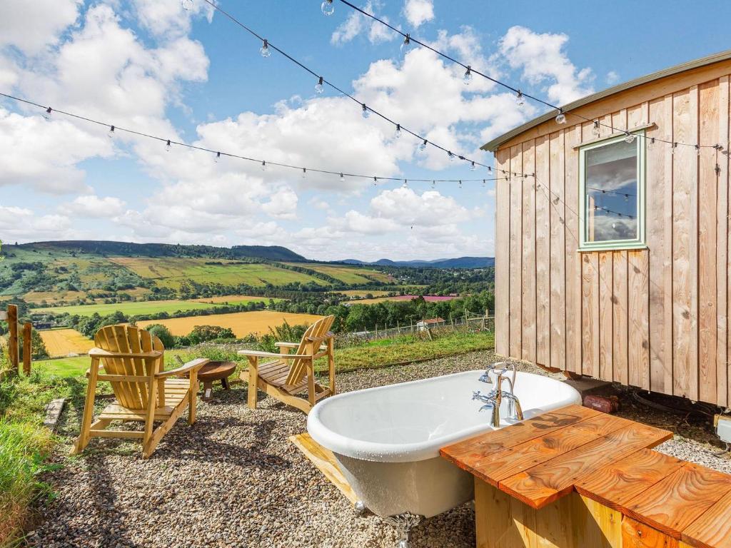 a bathroom with a tub and a table and chairs at Woodside Hut 1 - Uk36105 in Auchterneed