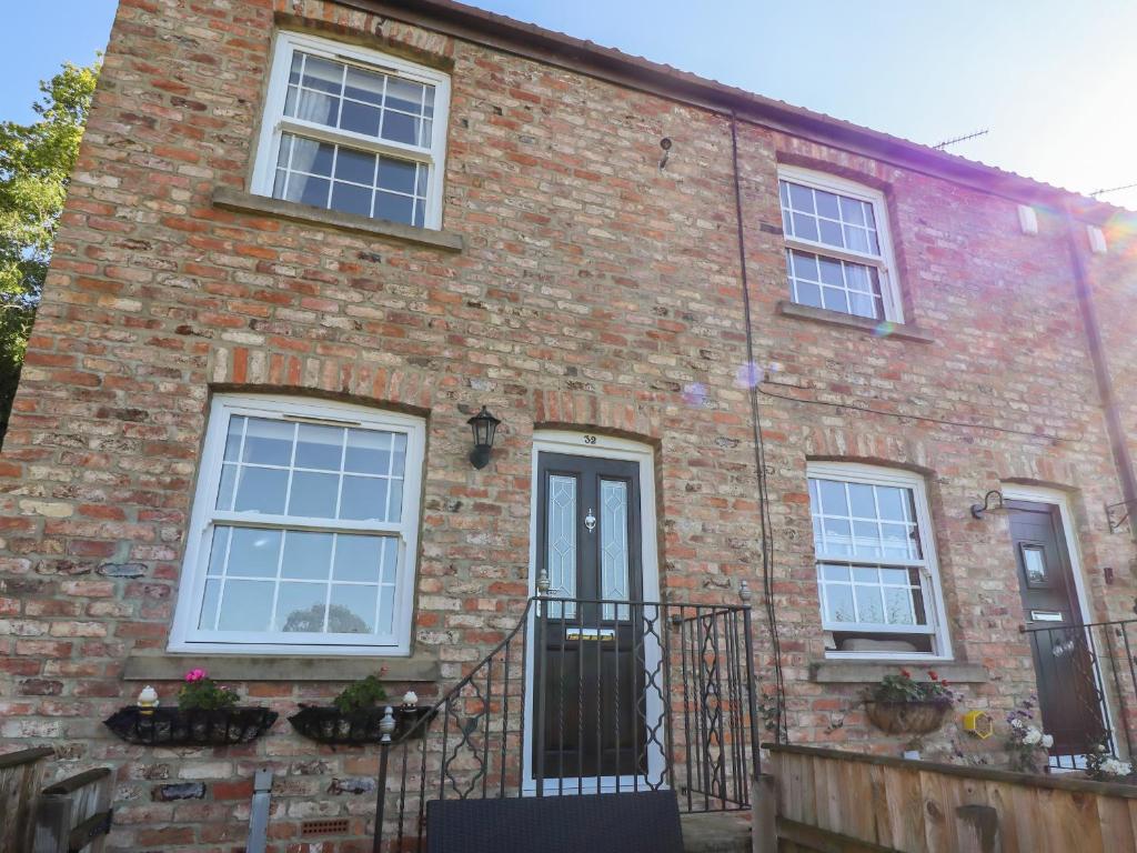 a brick house with white windows and a black door at Honeybee Cottage in Ripon