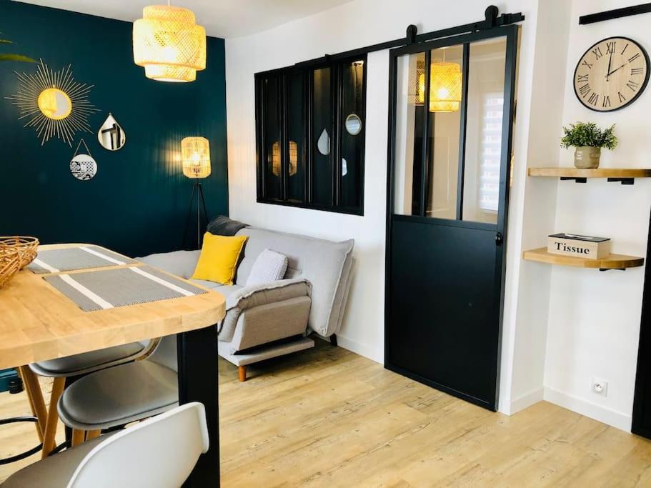 a living room with a table and a clock on the wall at Joli studio cosy in Châteaubriant