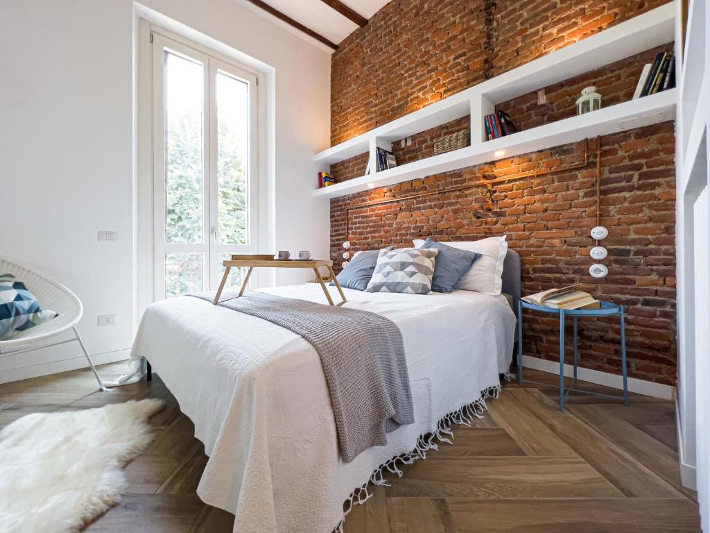 Un dormitorio con una pared de ladrillo y una cama en Emma's home Monza, en Monza