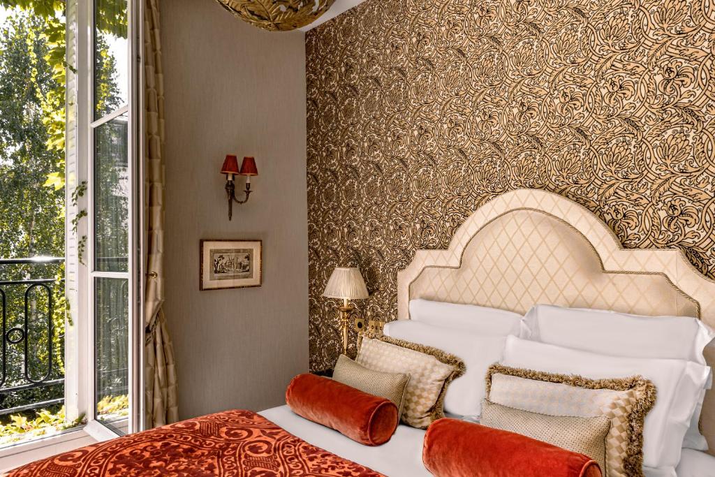 a bedroom with a large bed with a large window at Relais Christine in Paris