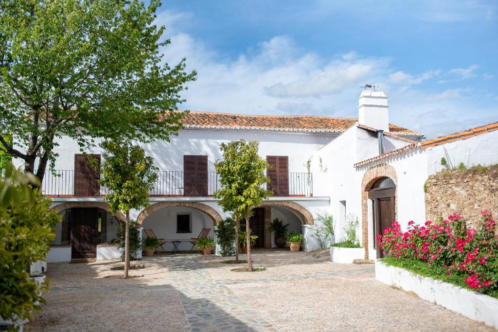 une maison blanche avec une cour ornée de fleurs roses dans l'établissement Finca El Azahar, à Trujillo