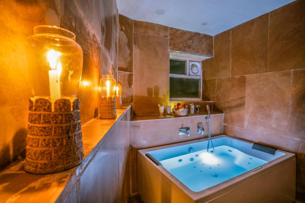 a bathroom with a tub with a candle and a sink at Casa De Kaku Jaisalmer in Jaisalmer