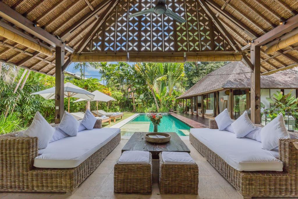 an outdoor patio with two couches and a pool at Bali Villa Home in Seminyak