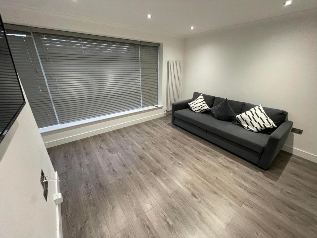 a living room with a couch and a large window at London West Ham Apartments in London