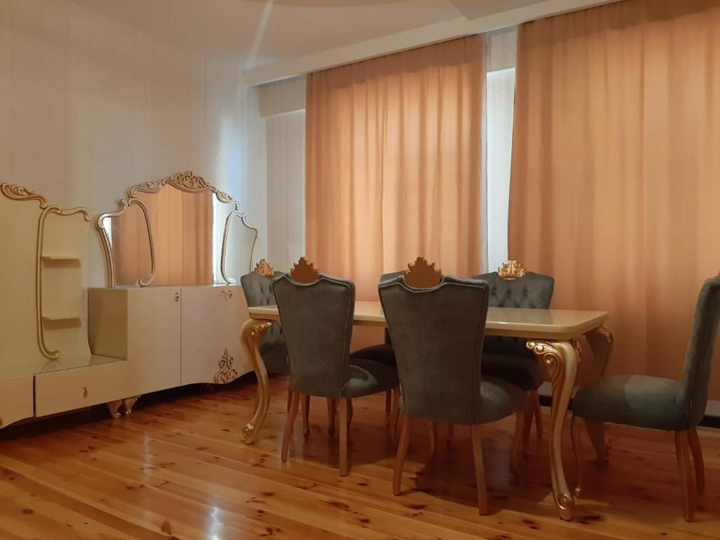 a dining room with a table and chairs and a mirror at My sweet home in Qara Qarayev in Baku