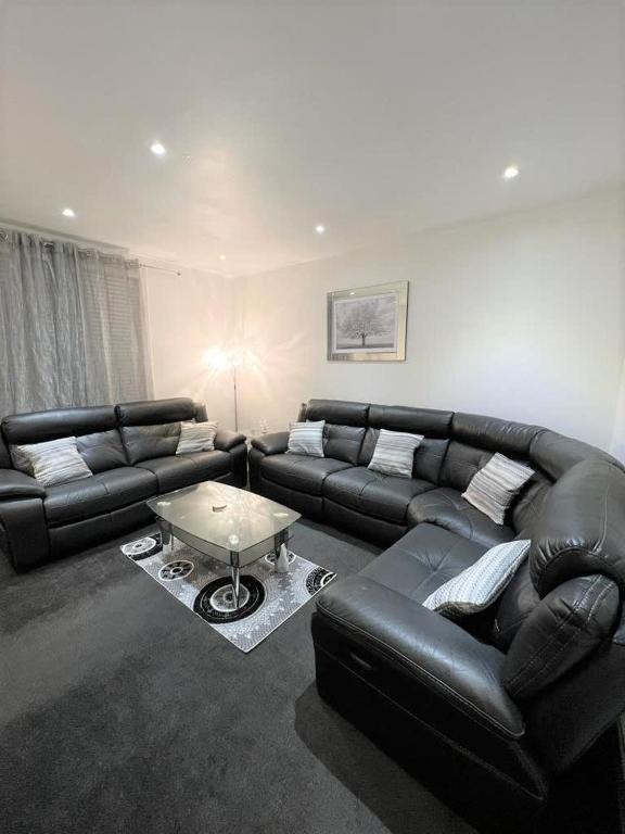 Lovely 2 Bed Apt close to Silverburn Mall في غلاسكو: غرفة معيشة مع أريكة جلدية وطاولة