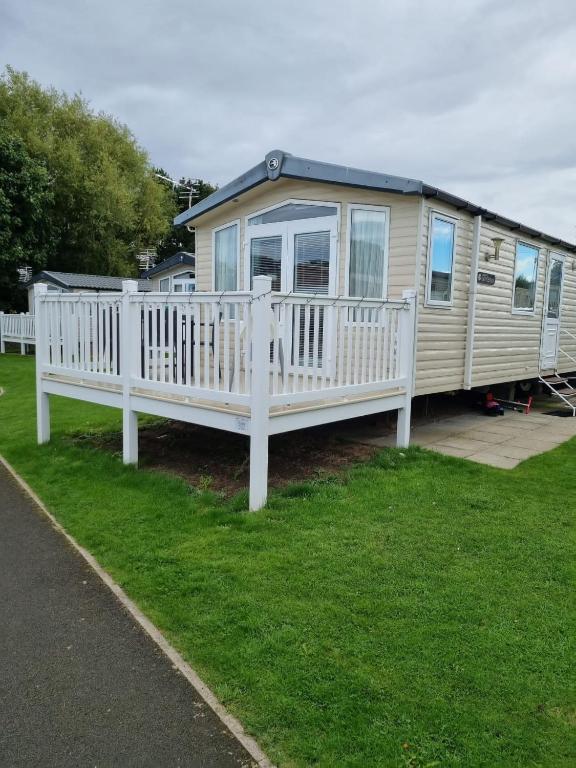 a mobile home with a white railing on the grass at Beautiful 3 bed holiday home in Port Seton