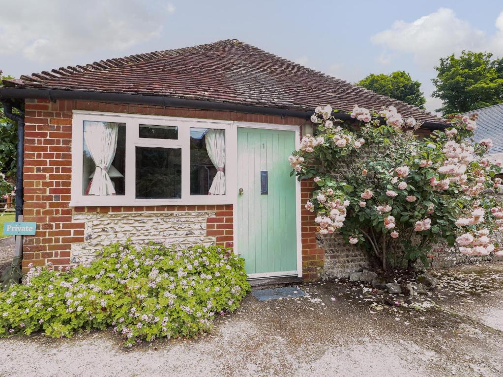 una casa de ladrillo con una puerta verde y una ventana en Byre Cottage 1 en Pulborough
