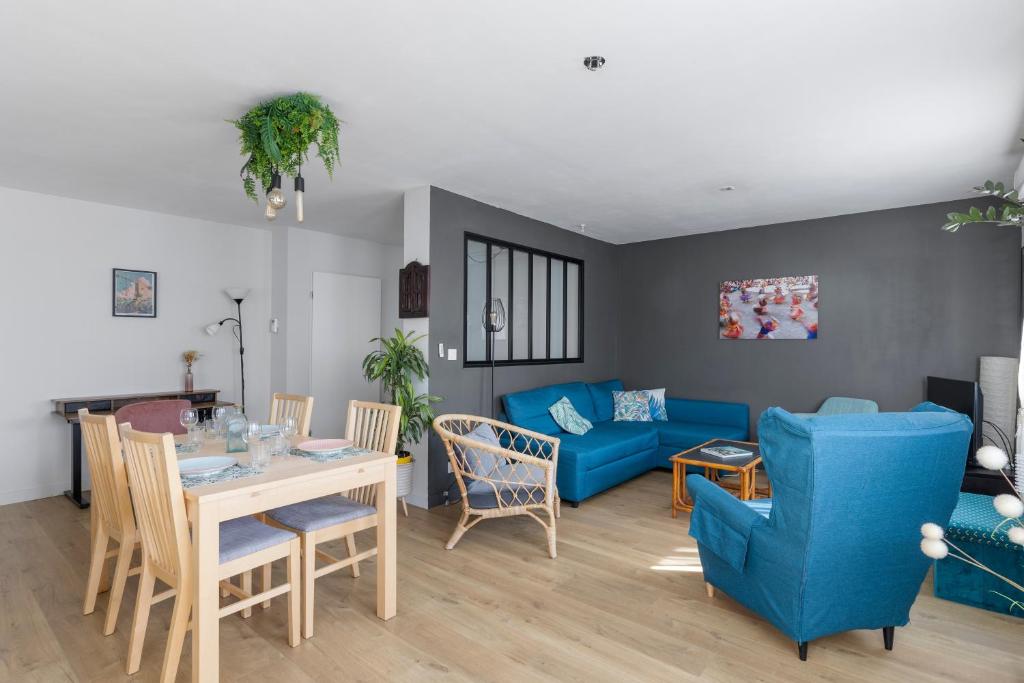a living room with a table and a blue couch at Le Manuka - avec terrasse et parking in Nantes