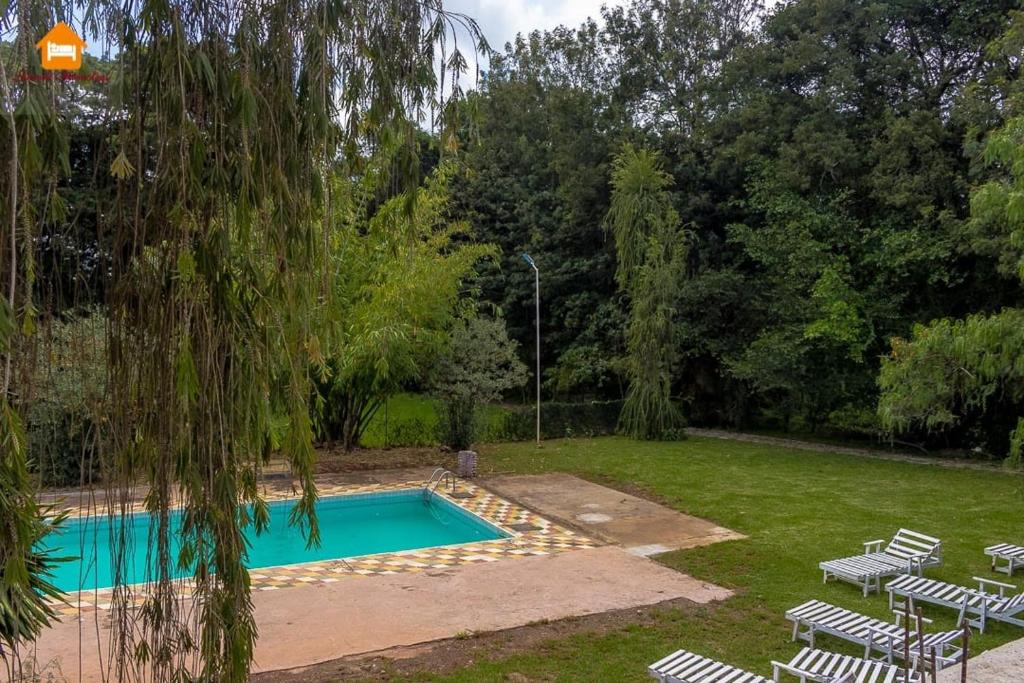 a swimming pool in a yard with chairs and a tree at Arabel Studio with Swimming Pool in Nanyuki
