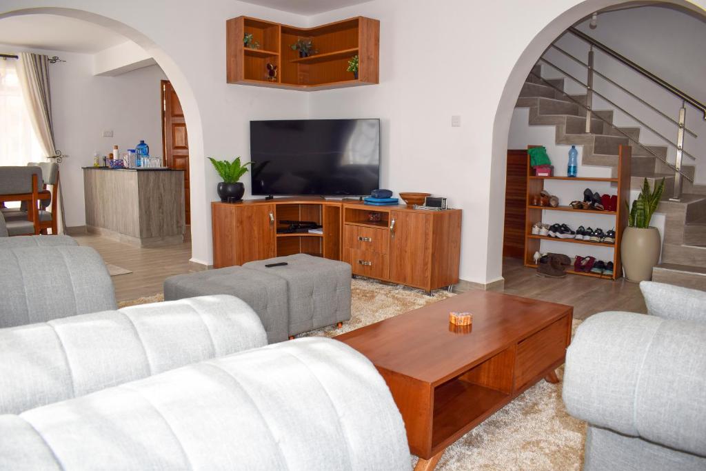 een woonkamer met een bank en een tv bij Cheerful 4-bedroom with pool in Athi River