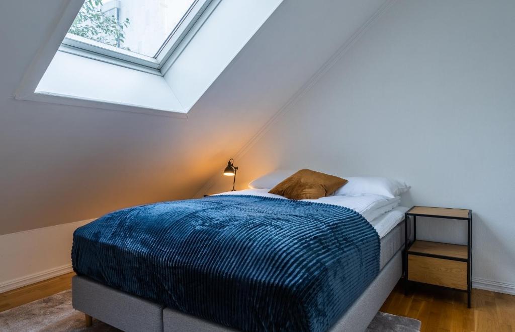 um quarto com uma cama com um edredão azul e uma janela em City Square em Tromsø