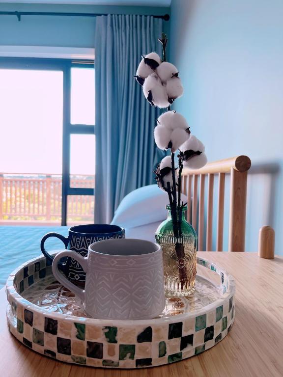 a tray with a cup and a vase with flowers on a table at Echo Lodge in Auckland