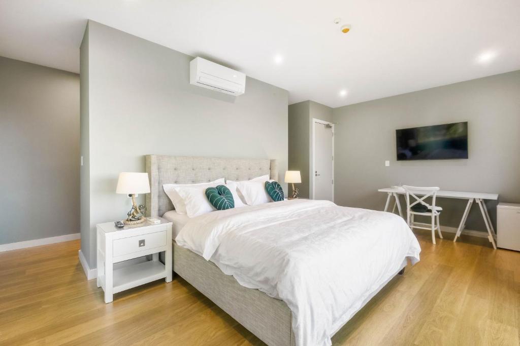a bedroom with a white bed and a table at Echo Lodge in Auckland