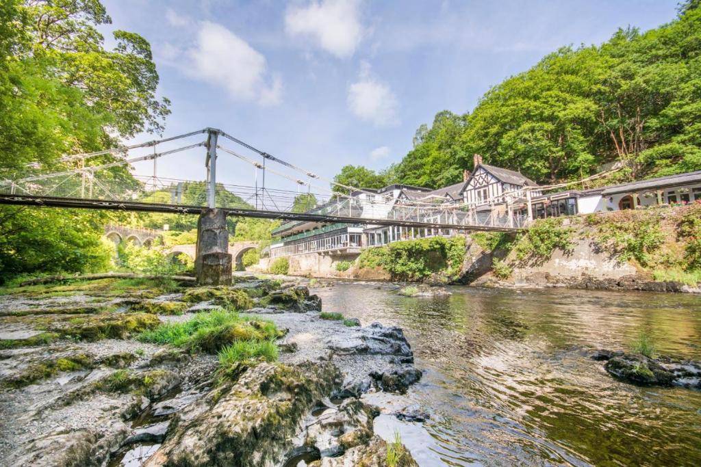 a bridge over a river with a train on it at The Chainbridge Hotel in Llangollen