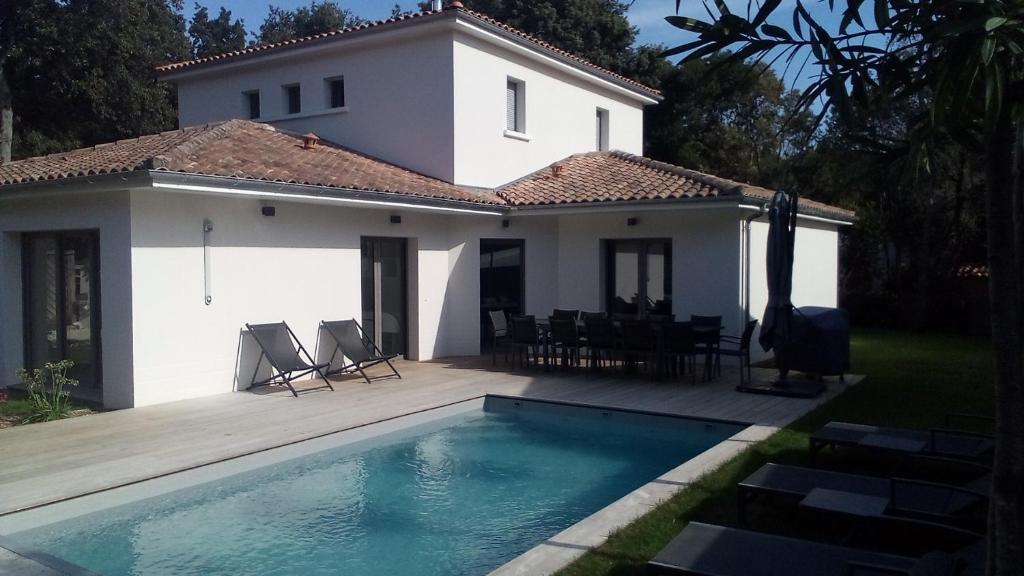 a villa with a swimming pool in front of a house at Villa- Vaux sur mer -200 m plage Nauzan - Piscine in Vaux-sur-Mer