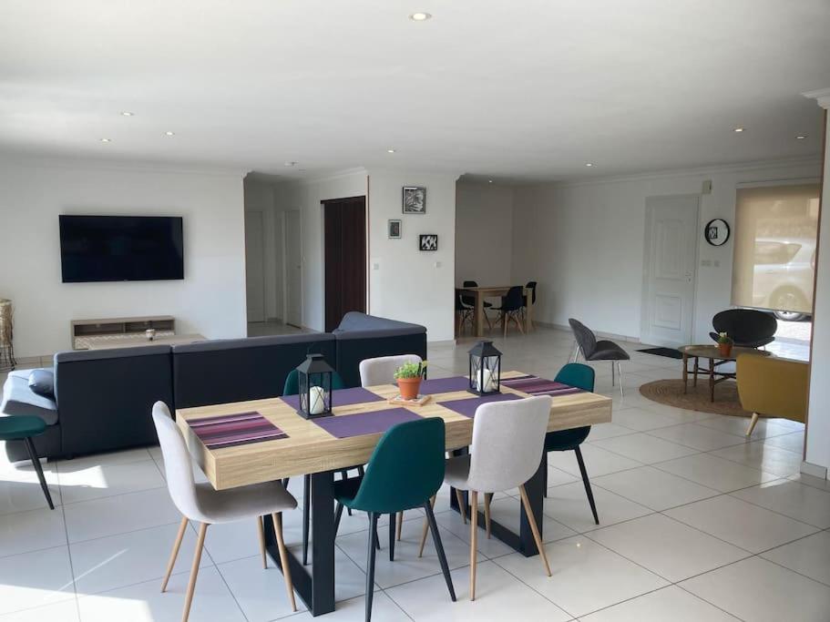 ein Wohnzimmer mit einem Tisch, Stühlen und einem Sofa in der Unterkunft Villa avec son spa privatif proche de Rocamadour in Gramat
