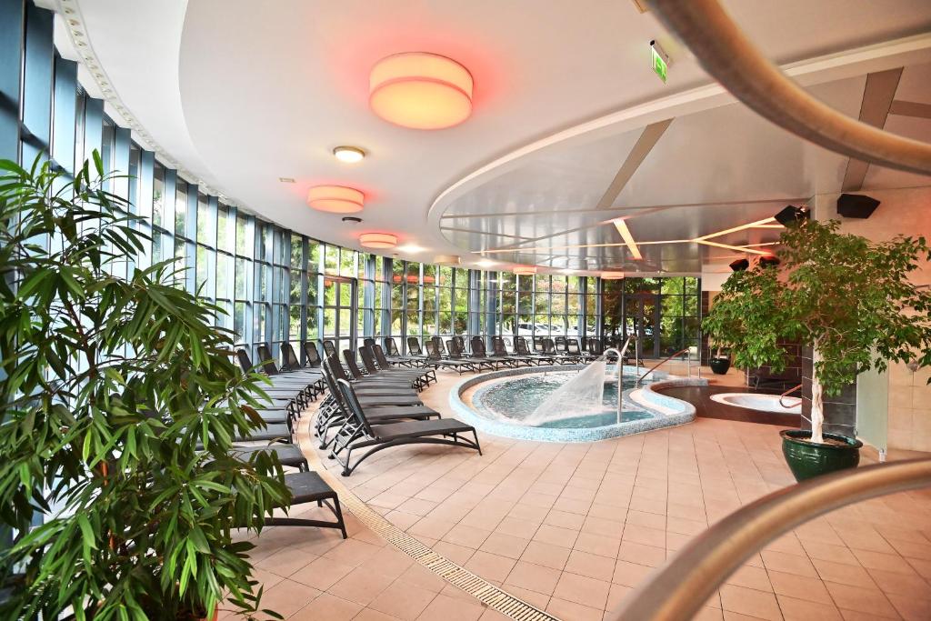 un gran edificio con bañera de hidromasaje y sillas en Hotel Eger & Park, en Eger