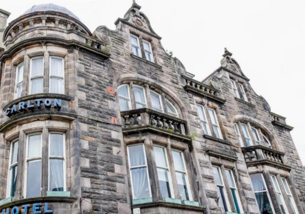 an old stone building with windows and a sign on it at Carlton Hotel in Forres