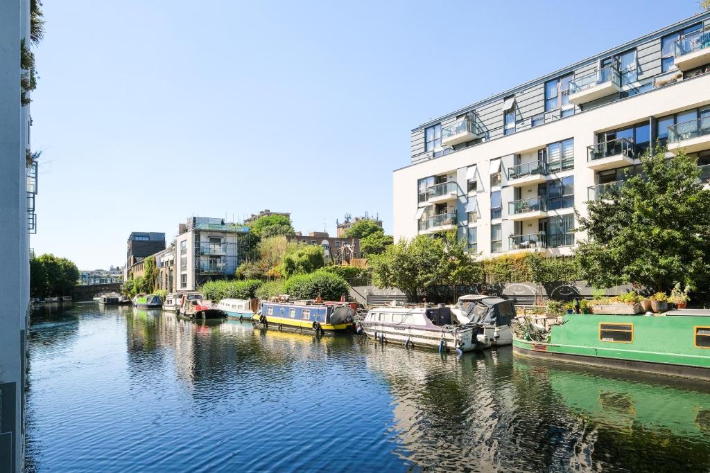 a group of boats docked in a river with buildings at Lovely 2 bed flat in canal side gated development in London