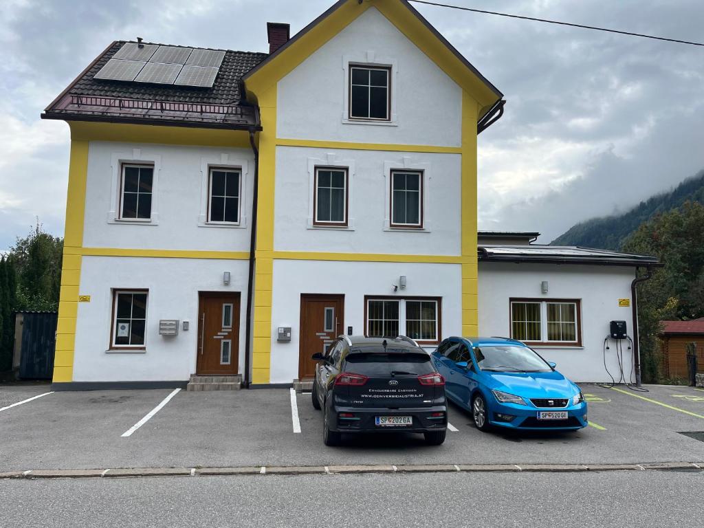 two cars parked in front of a yellow and white house at Ferienwohnung Möllbrücke in Möllbrücke
