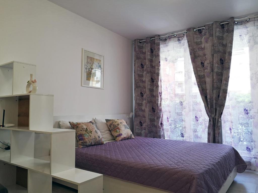 a bedroom with a purple bed and a window at Comfortable Ground Floor Studio in Primorsko