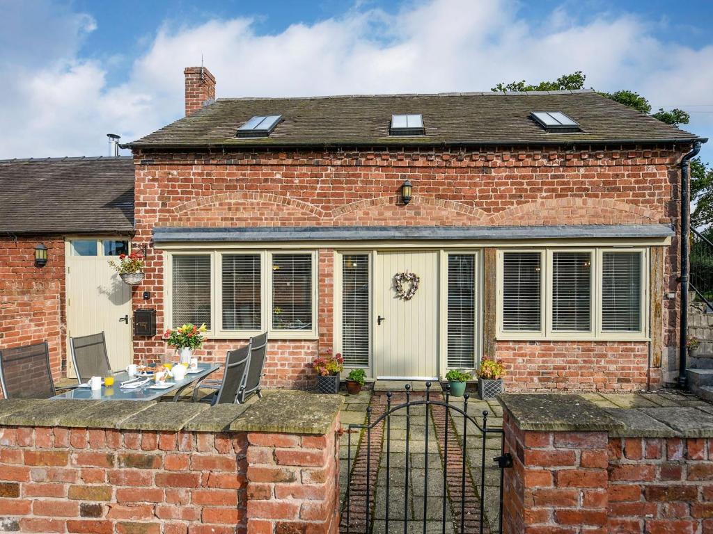 a brick house with a gate and a patio at Grove Farm Cottage in Condover